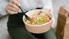 Person holding fork and healthy meal in takeout container